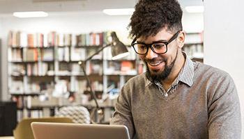 Male student working on a laptop in a library