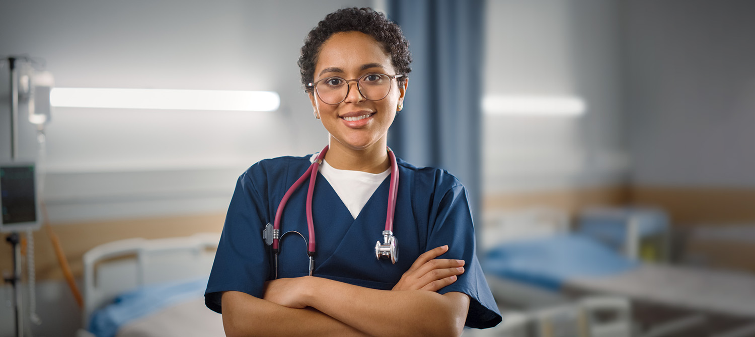 Photo of medical worker in hospital room looking at camera and smiling.