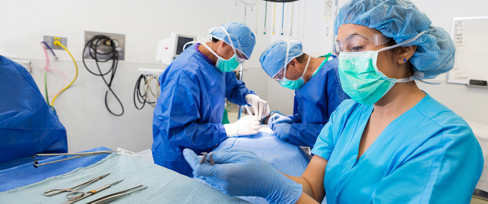 A surgical technician in a operating room with doctors.